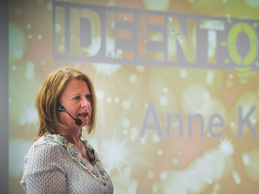 Anne Knapp spricht mit Headset-Mikrofon vor einer Leinwand